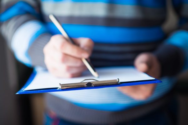 businessman holding a clipboard and write on it